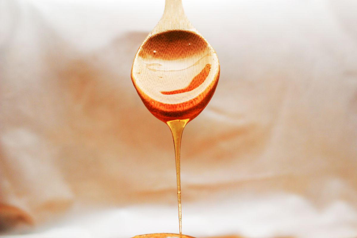 Goldener Honig tropft von einem Holzlöffel